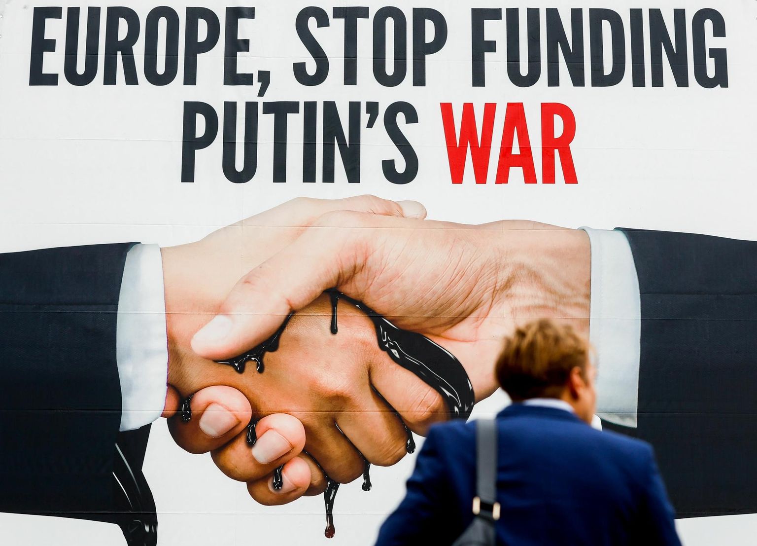 Plakat Brüsselis, mis kutsub Euroopat peatama Putini sõja rahastamist. 