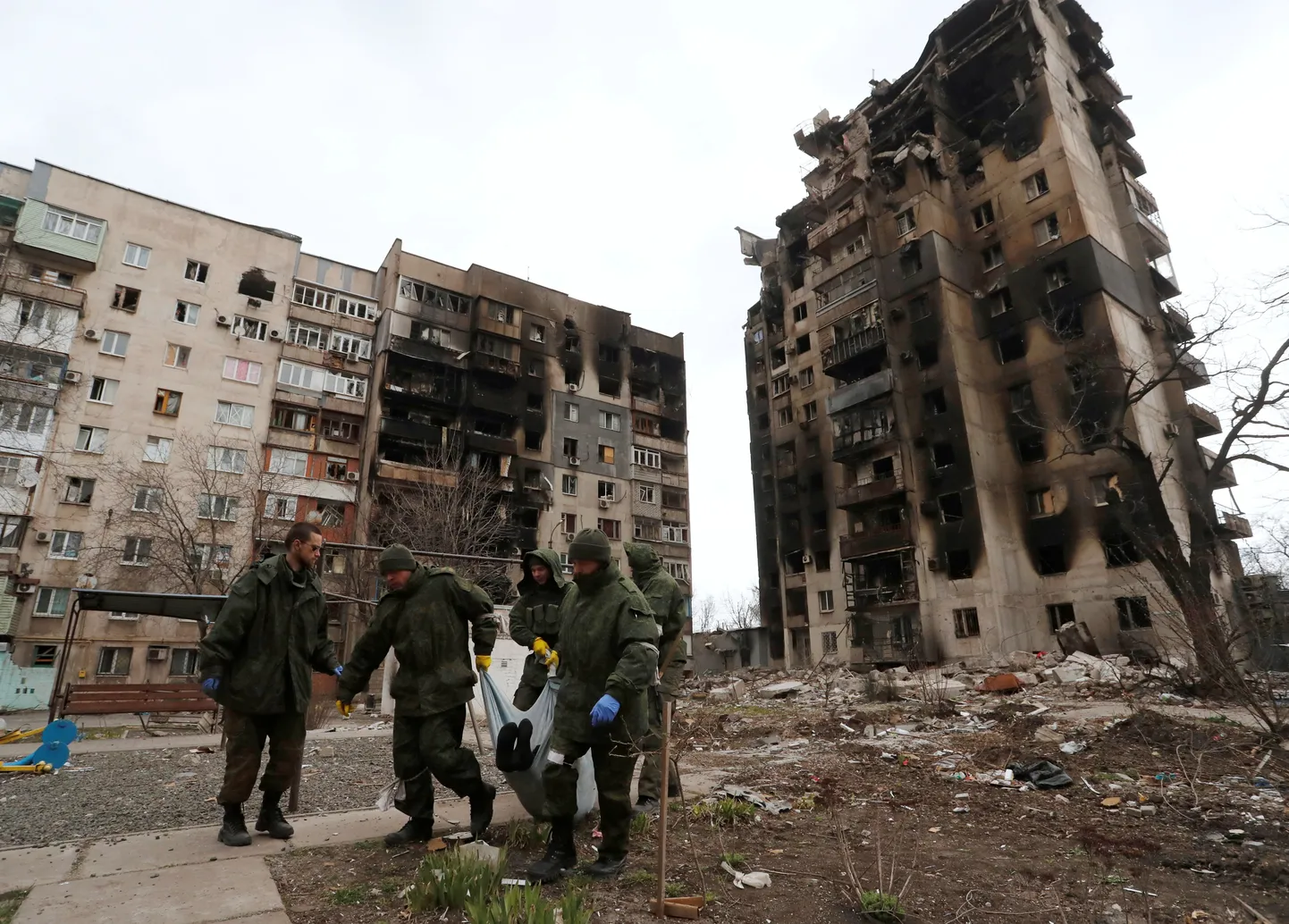 Foto 4. aprillist, kus Vene väed Mariupolis tassivad laibakotti purustatud elumaja taustal.