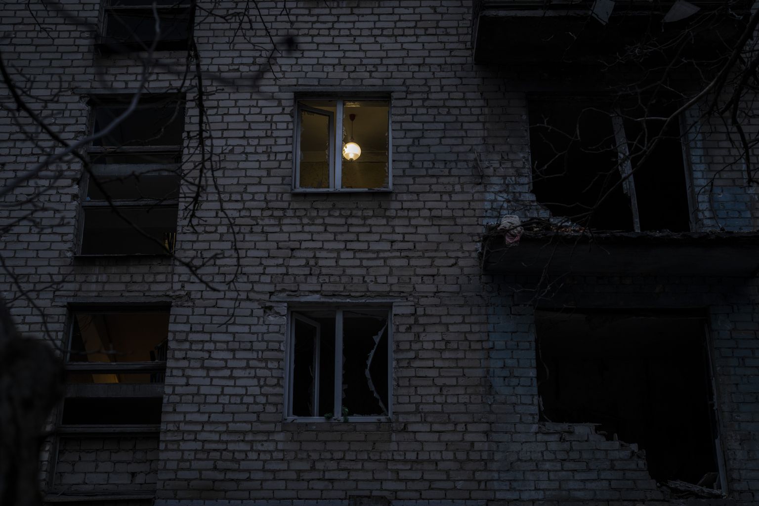 Ukraina lõunaosas Hersoni linnas valgustab lamp Venemaa streigi ajal hiljuti kannatada saanud hoone ruumi.
