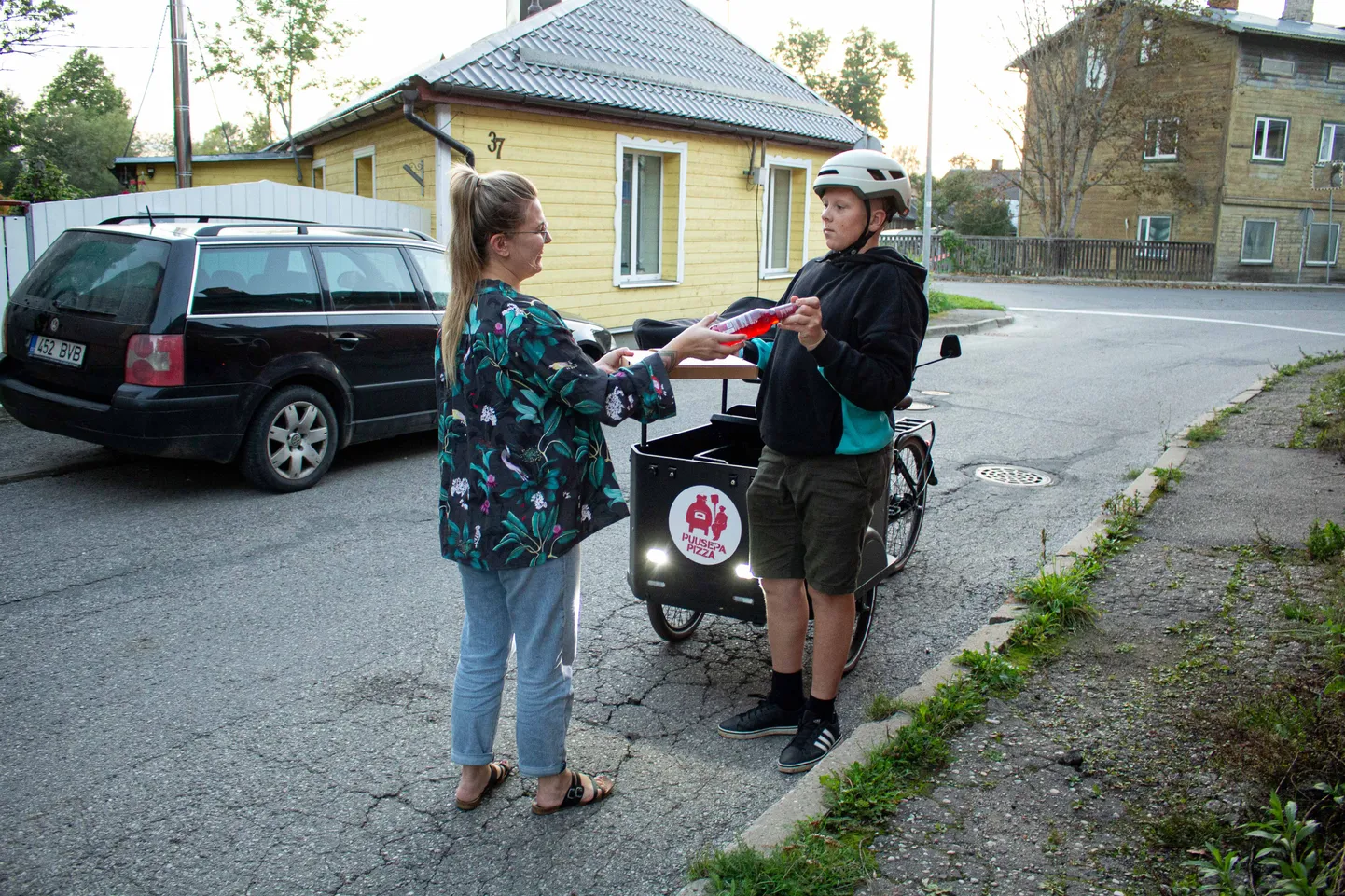 Puusepa Pizza kojutoomisteenuse esimeseks kliendiks osutus valgalanna Maarja Appo, kes pildil kuller Mark Laarilt pitsat vastu võtab.