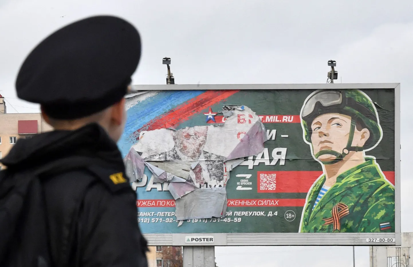 Sõjaväelane silmitsemas katki rebitud armeeplakatit Peterburis 5. oktoobril 2022.