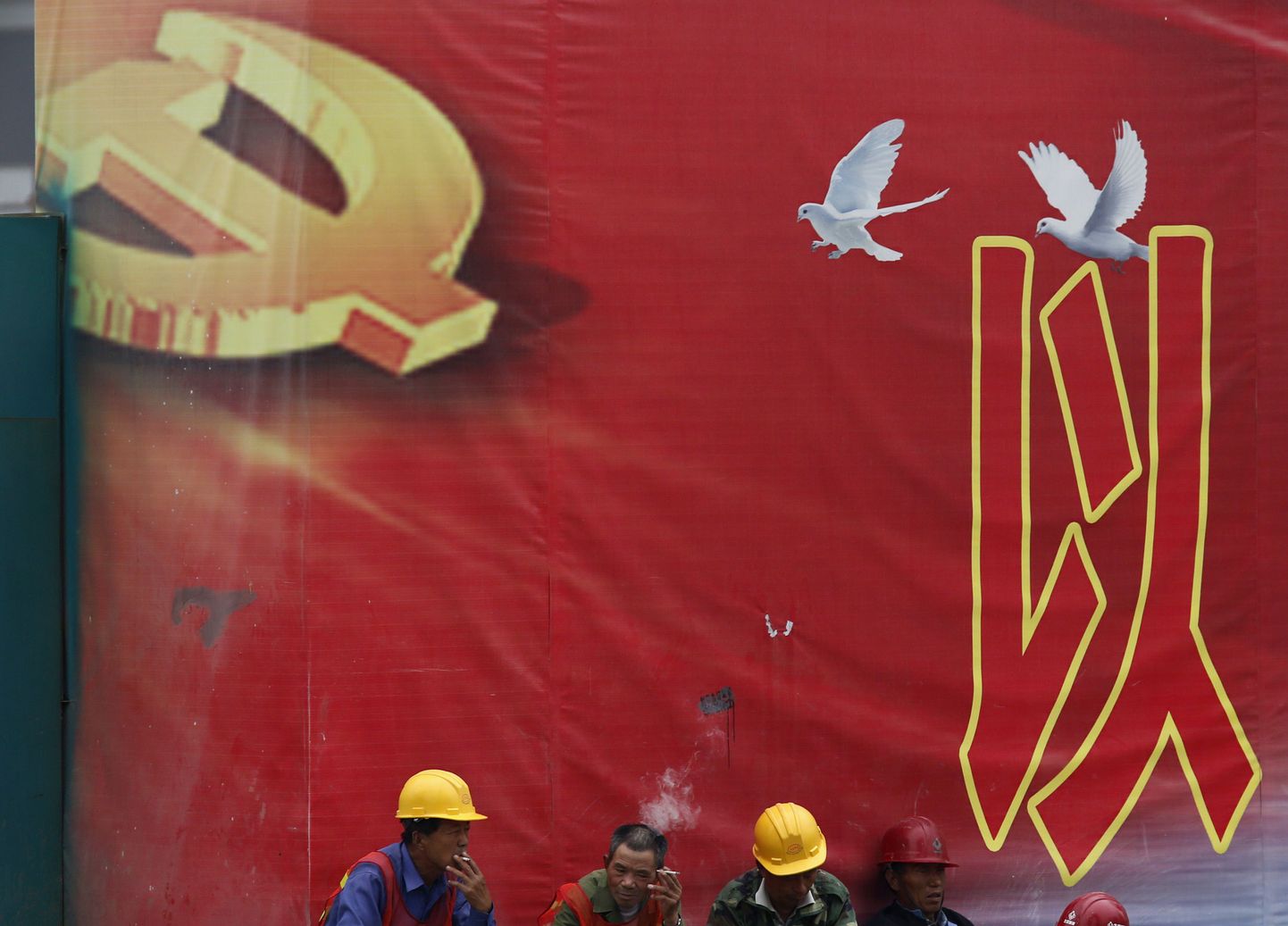 Töölised Hiina Kommunistliku Partei embleemi taustal.