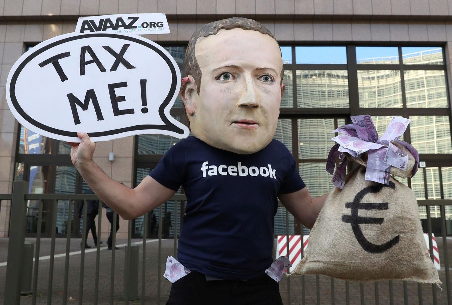 Brüsseli aktivist avaldab tehnohiiu maksutamise nimel meelt, Mark Zuckerbegi mask ees.