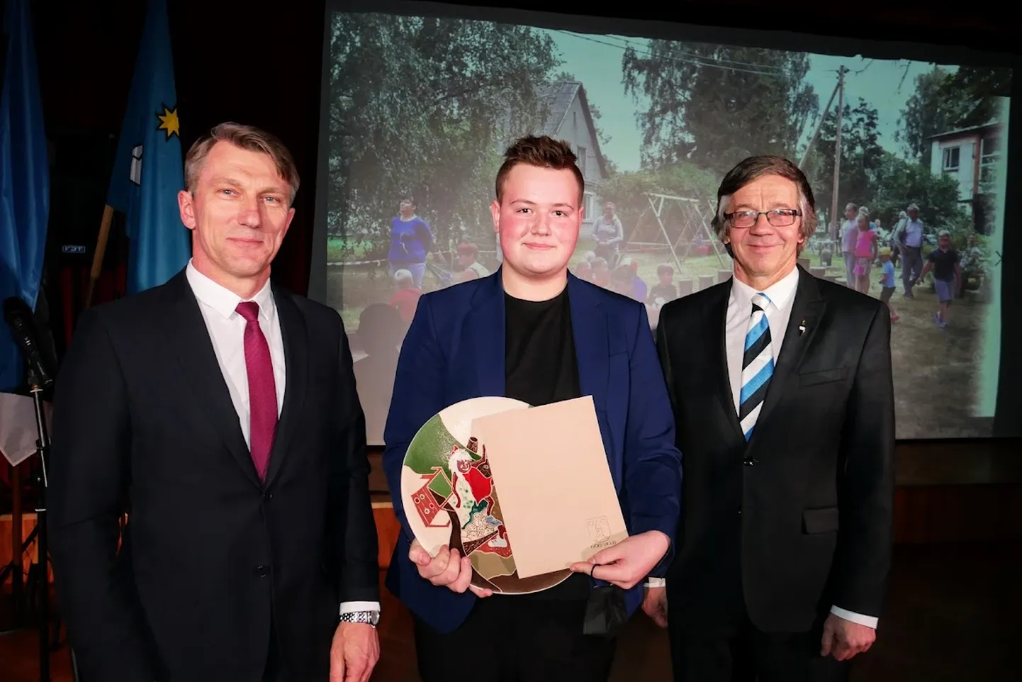 Nõo vallavanem Maano Koemets (vasakul) ja vallavolikogu esimees Jaanus Järveoja (paremal) andsid Martin Lilleverele üle aasta tegija auhinna.