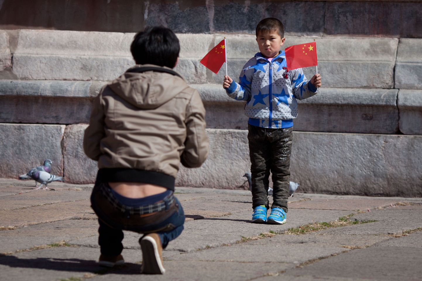 Hiina poiss hoiab Pekingis käes kahte riigilippu, poseerides nii oma isale.