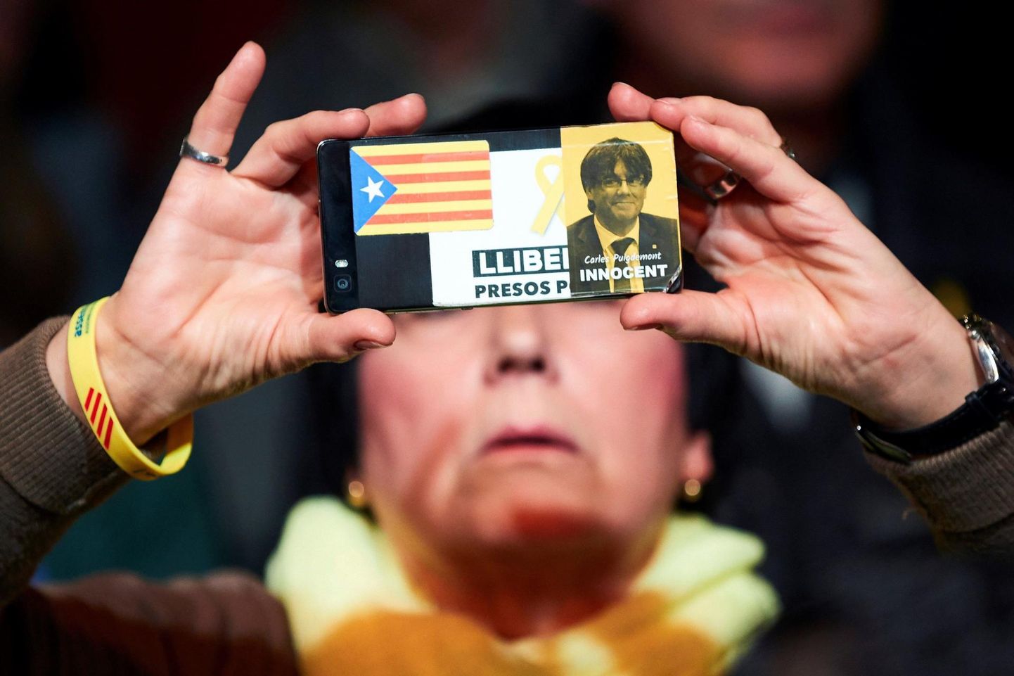 Kataloonia iseseisvusmeelse partei JxCat üritus Barcelonas. Telefoni tagaküljele pandud kleebisega üritatakse edasi anda sõnumit Carles Puigdemonti süütusest.