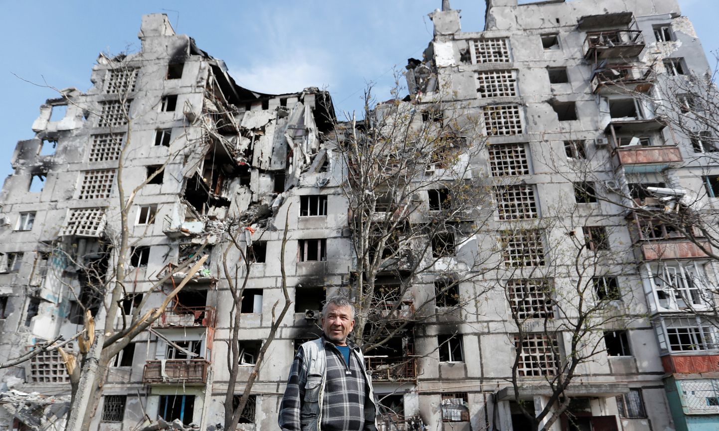 Mariupoli elanik sõjategevuses purustatud kortermaja ees.