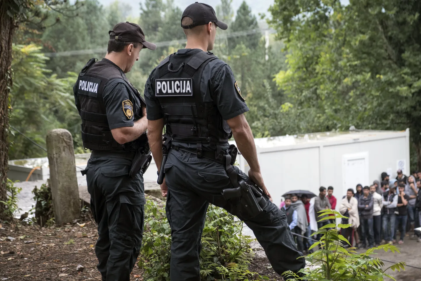 Bosnia politseinikud migrante valvamas.