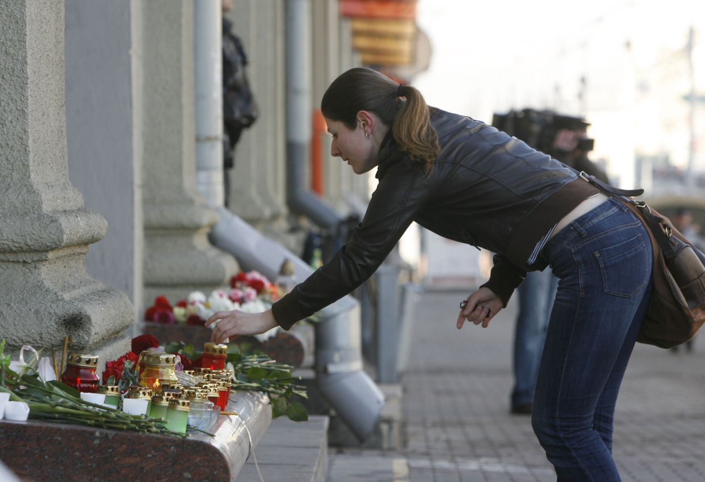 Девушка ставит свечку в память о погибших в теракте.