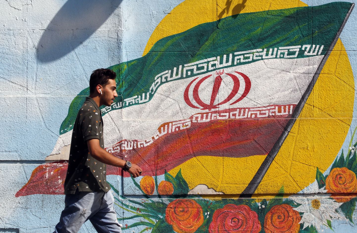 Iraani poiss kõnnib Teheranis Iraani riigilippu kujutavast seinamaalist mööda.