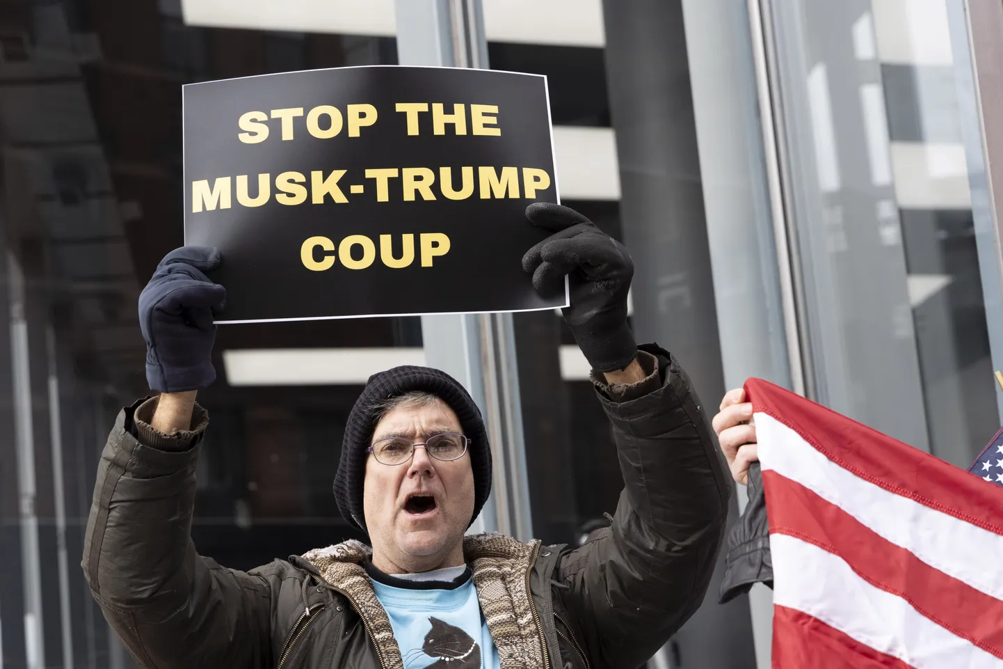 Meeleavaldaja hoiab silti kirjaga „PEATAGE MUSK-TRUMPI RIIGIPÖÖRE“ Tesla müügisalongi ees Manhattani West Village'is. Aktivistide rühmitus Rise & Resist protesti „Stop the Musk-Trump Coup“ vastuseks president Trumpi ja Elon Muski tegevusele Ameerika Ühendriikide DOGE teenistuses.