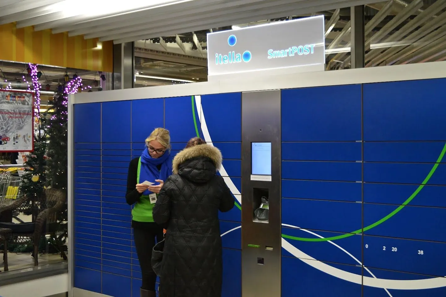 Itella Smartpost abitöötaja Tallinna Magistrali keskuse pakiautomaadi juures.