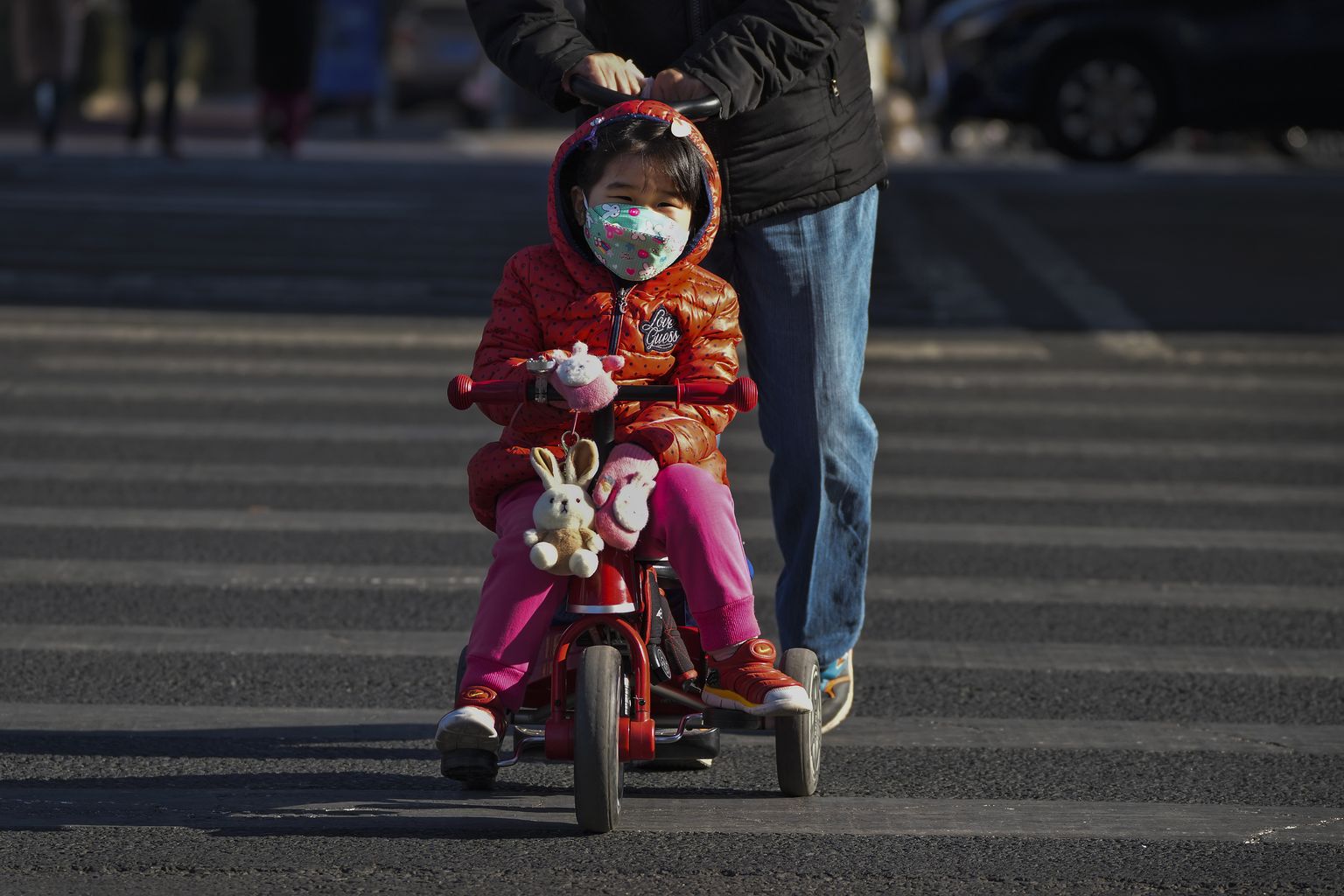 Naine lükkab jalgrattal last Pekingi tänavatel, 4. jaanuar 2023. a.