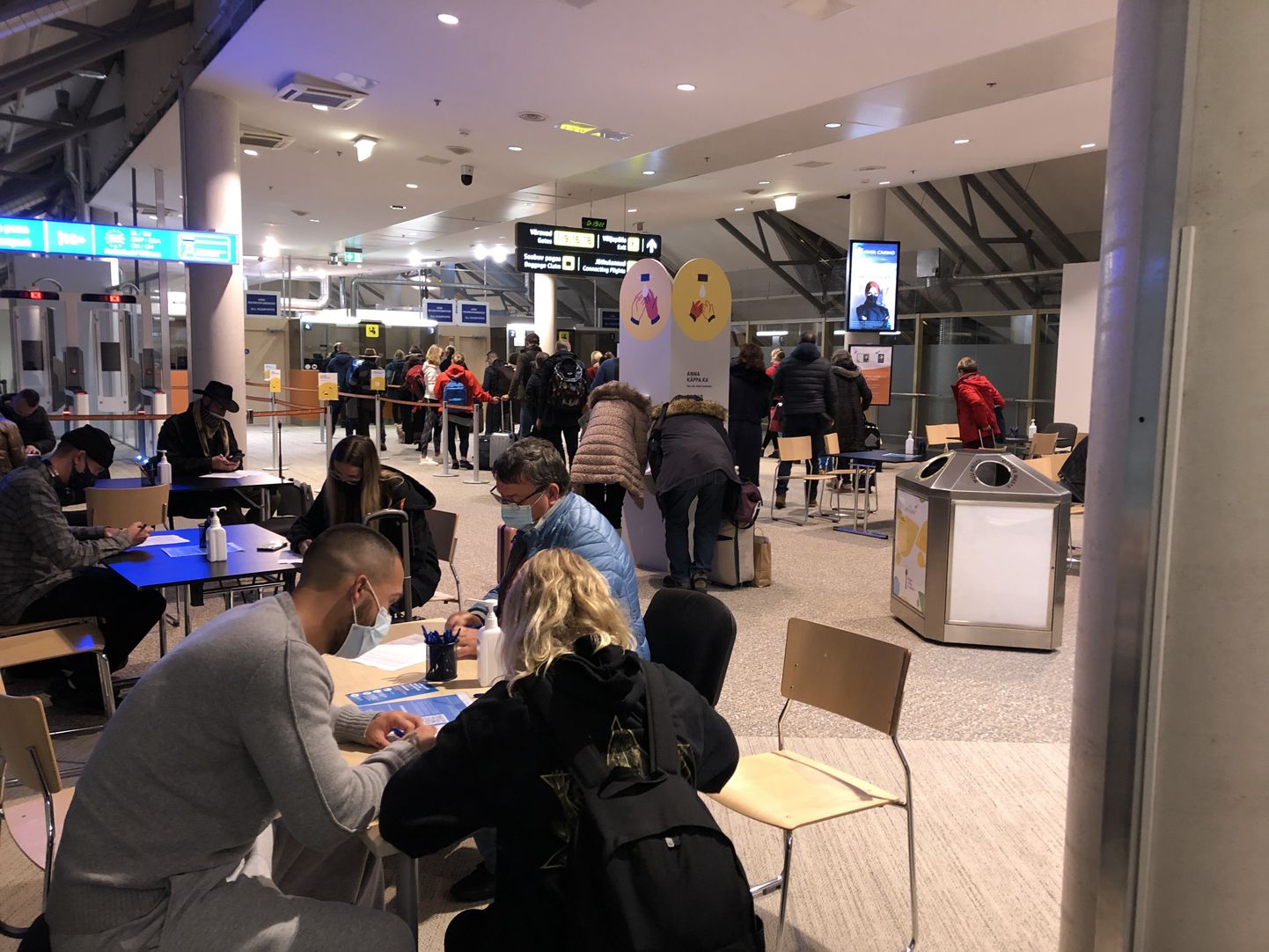Inimesed Tallinna lennujaamas paberil tervisedeklaratsioone täitmas.