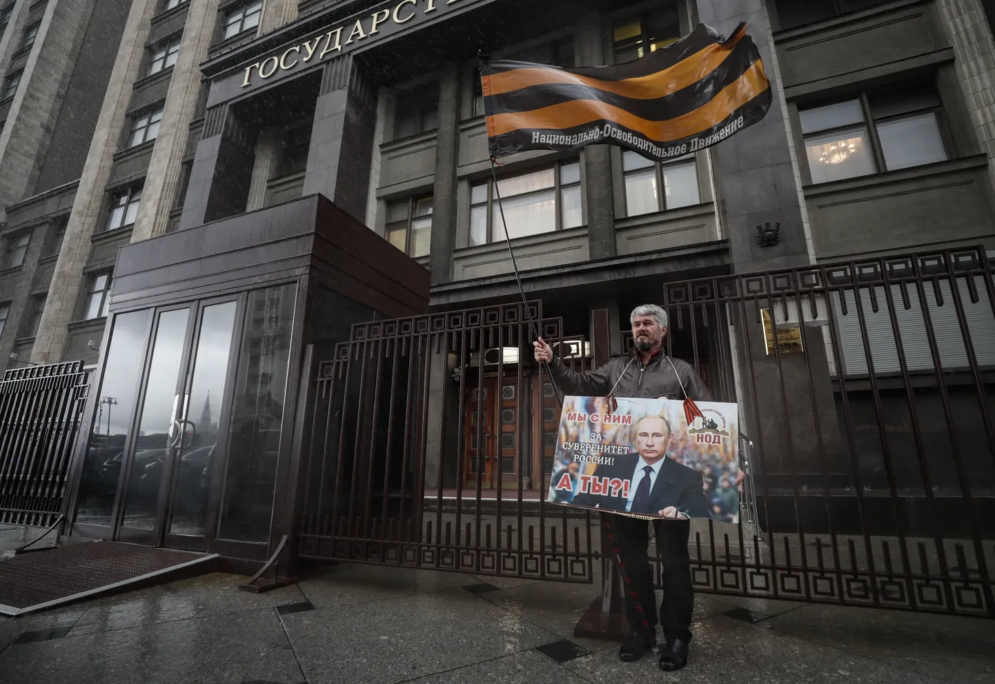 Mees hoiab täna Moskvas riigiduuma hoone eest plakatit Vladimir Putini pildi ja tekstiga: «Meie oleme temaga. Kas sina oled? Venemaa suveräänsuse nimel.»