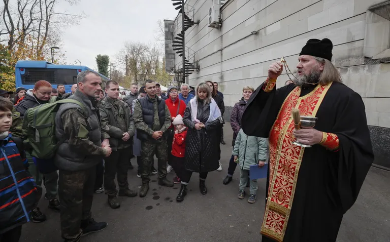 Священник благословляет мобилизованных на войну.