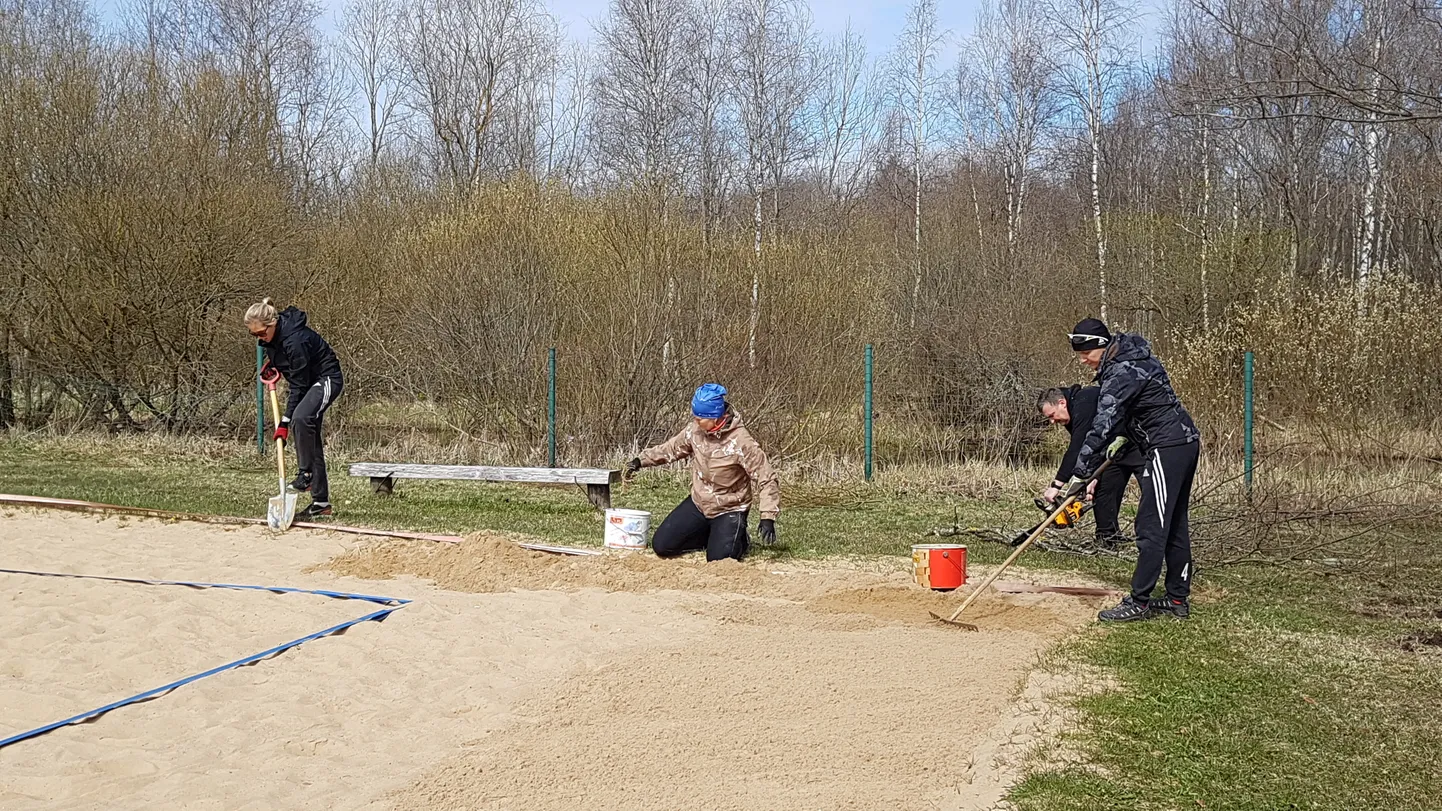 Nele Mangmann (vasakult), Piret Reinfeld ja Maive Sibul rohivad liivaväljaku servad puhtaks.