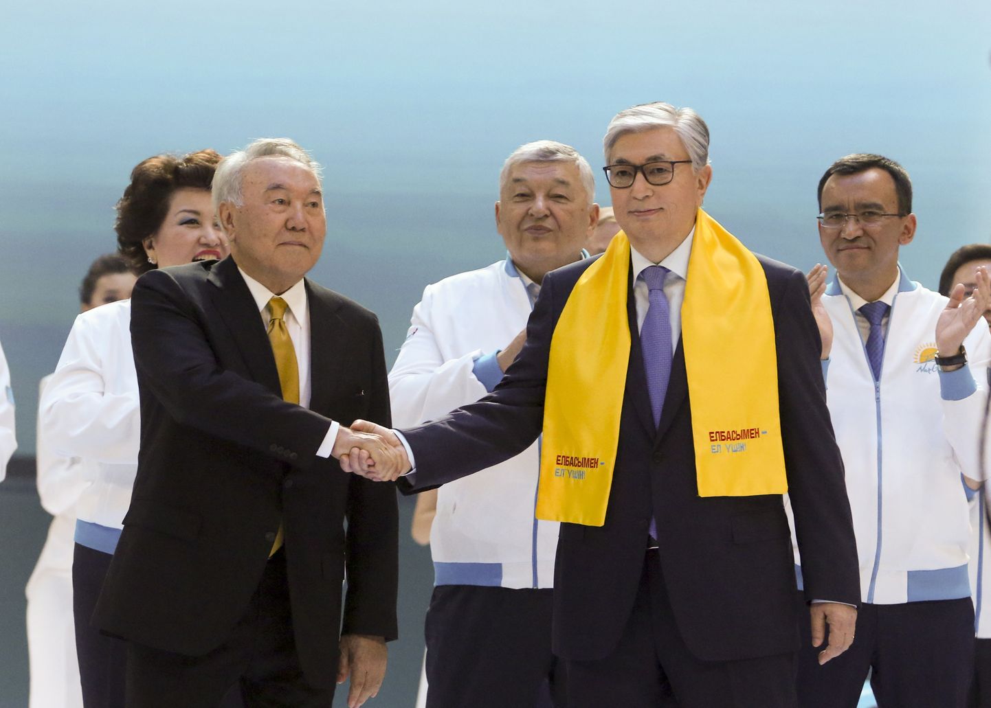 Kasahstani presidendikandidaat Kassõm-Žomart Tokajev (kollase salliga) ning riigi endine president Nursultan Nazarbajev kätlemas valimisüritusel.