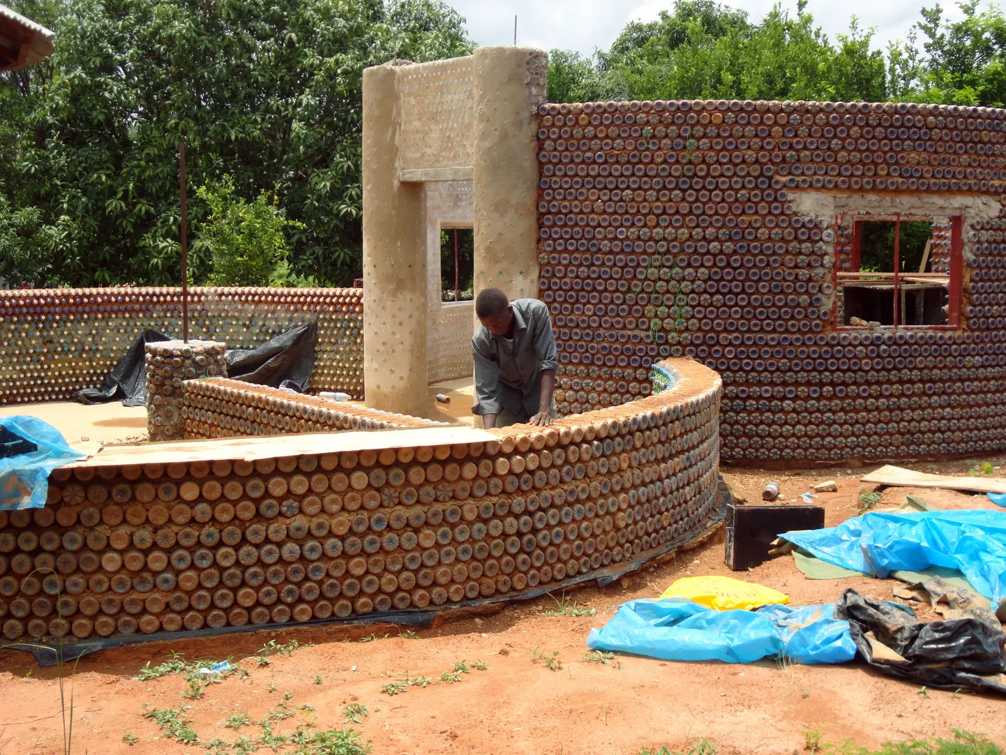 TO GO WITH AFP STORY BY AMINU ABUBAKAR
A man builds on November 2, 2011 a wall with plastic bottles in the village of Sabon Yelwa, near the northern Nigerian city of Kaduna. The idea undoubtedly seemed strange at first: Take the plastic water bottles that litter Nigeria's roads, canals and gutters and allow people to live inside them. The project was initiated by the Kaduna-based NGO Development Association for Renewable Energies (DARE), with help from foreign experts from Africa Community Trust, a London-based NGO.    AFP PHOTO / Aminu ABUBAKAR