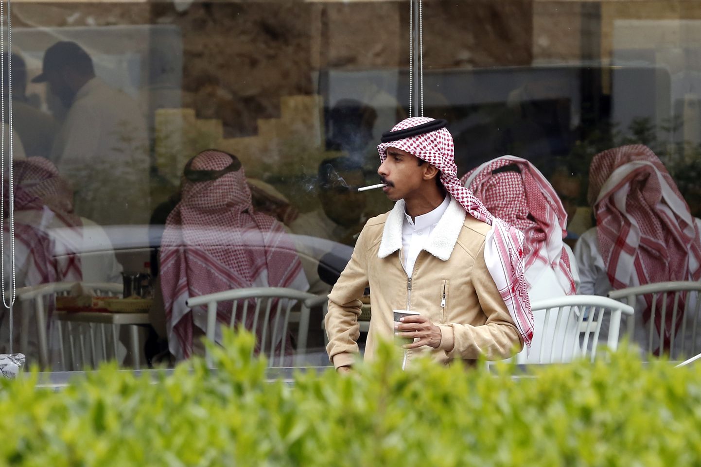 Saudi mees suitsetamas vallalistele mõeldud restorani ees.