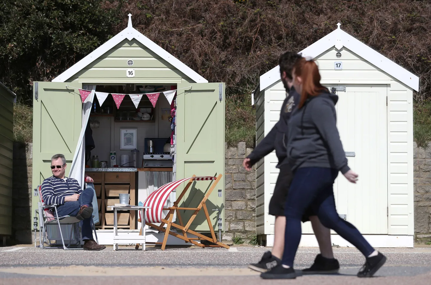 A beachgoer sits outside his beach hut on Bournemouth Beach in Dorset.