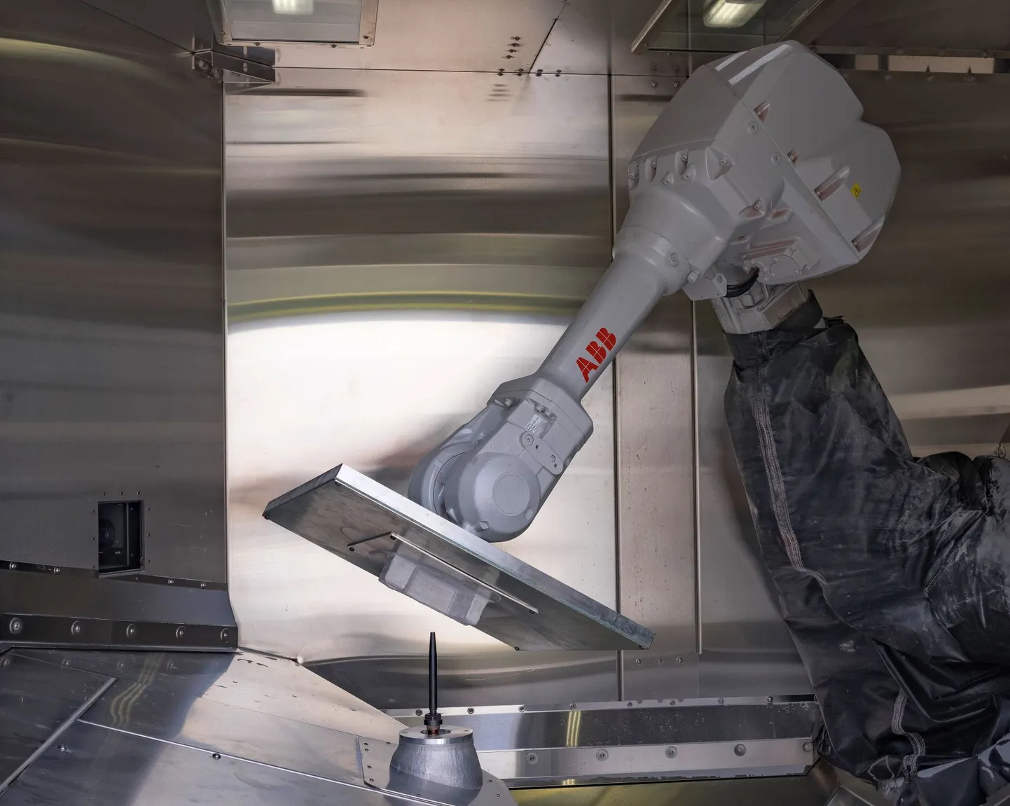 Moodsa remonditöökoja sisemuses: ABB robotkäsi tõstab välja äsja külmalt valmis saanud metalldetaili.