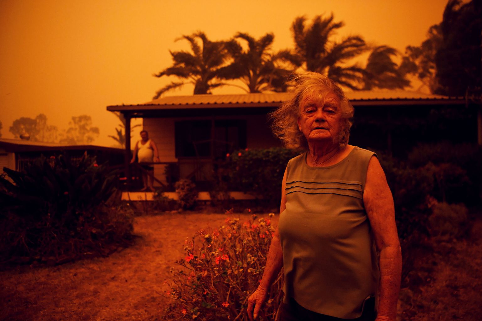 Sieviete un vīrietis stāv pie savas mājas Austrālijas savvaļas ugunsgrēku laikā 2020. gada janvārī.