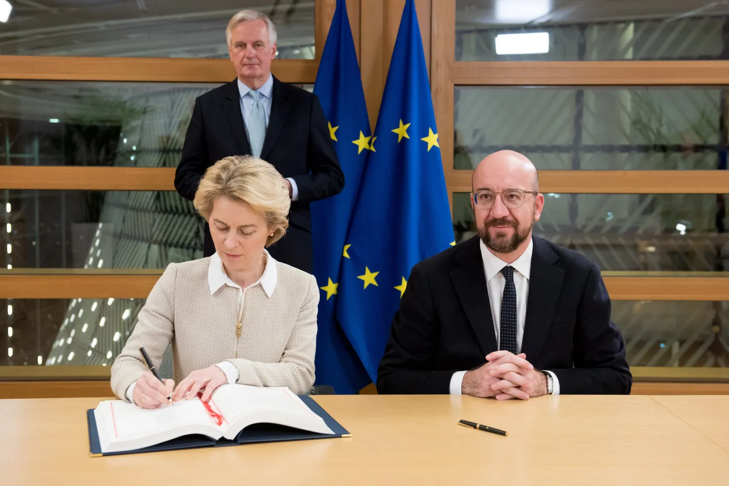 Euroopa Komisjoni juht Ursula von der Leyen allkirjastamas lepet, mille alusel Ühendkuningriik Euroopa Liidust lahkub. Tema vasakul küljel istub Euroopa Ülemkogu juht Charles Michel ja nende seljataga EL-i Brexiti pealäbirääkija Michel Barnier.