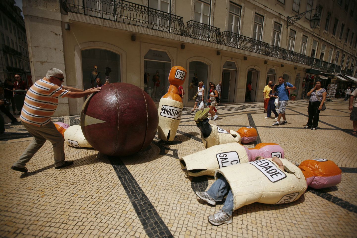 Португальцы протестуют против политики МВФ и европейских институтов власти, которую символизирует шар для боулинга. В роли кеглей, естественно, португальцы и их проблемы.