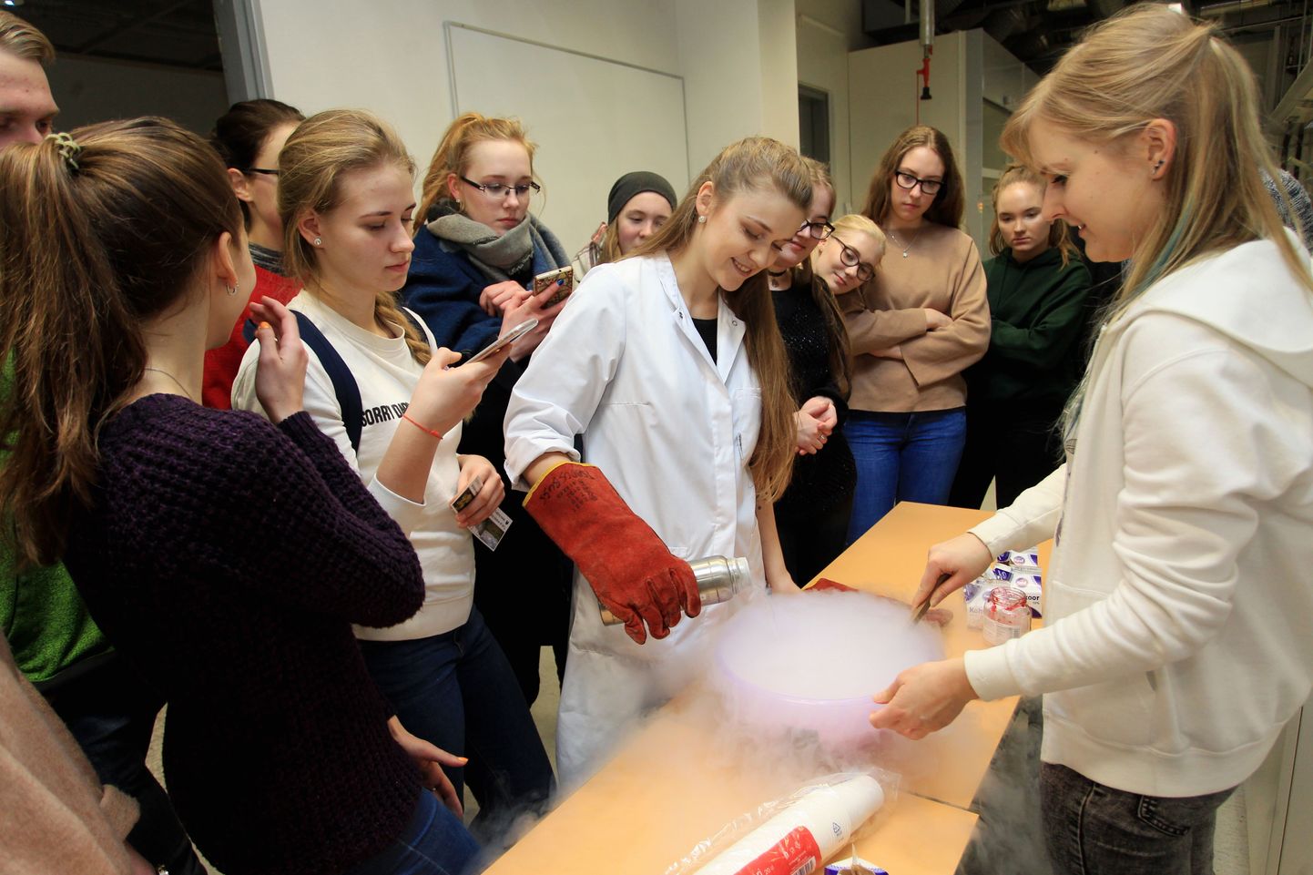 Loodus- ja täppisteaduste valdkonna üliõpilased Airiin Hango (vasakult) ja Eliise Tammekivi näitavad tulevastele tudengitele, kuidas pärast vedela lämmastiku lisamist moosile ja koorele saab kiiresti ja efektselt jäätist valmistada.