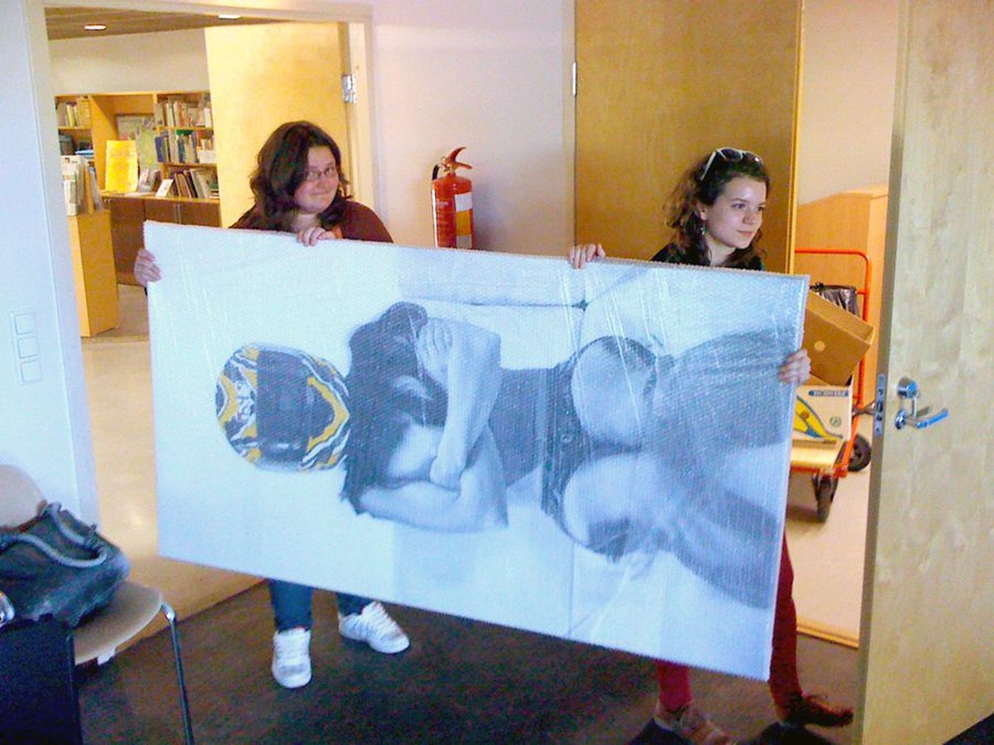 Kunstikooli õpilased Rita Puhu ja Kerly Ritval (paremal) tassivad näitusetöid galeriisse.