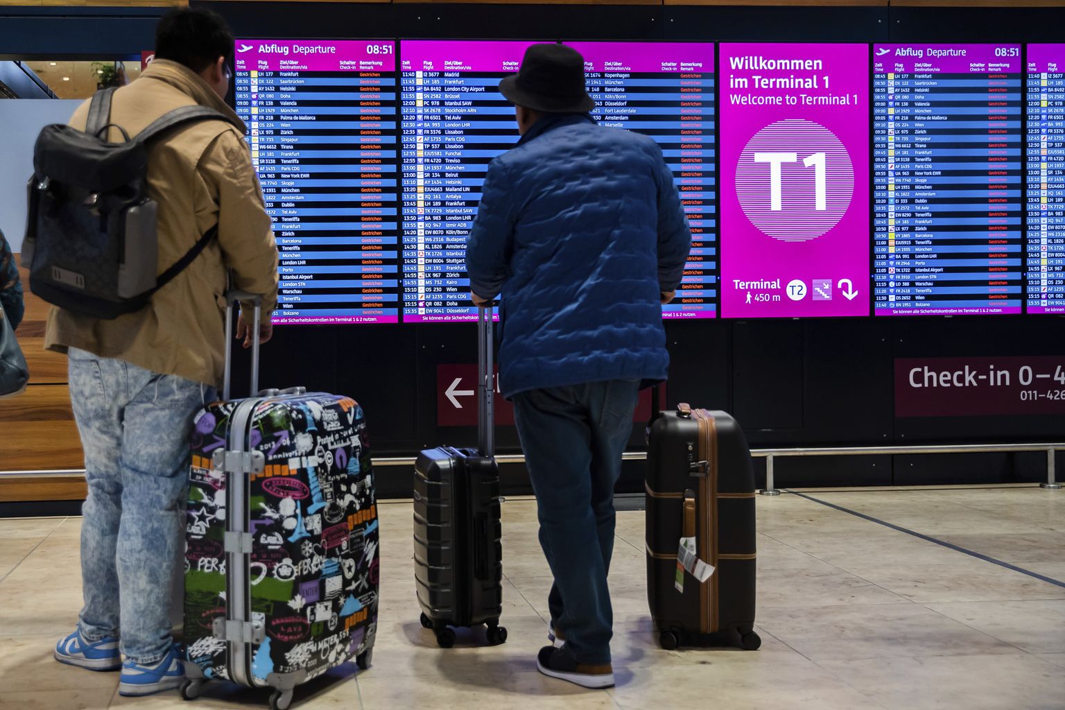 Пассажиры смотрят на табло, показывающее, что все рейсы отменены во время предупредительной забастовки в аэропорту Берлин-Бранденбург (BER) в Германии в среду, 25 января 2023 года.