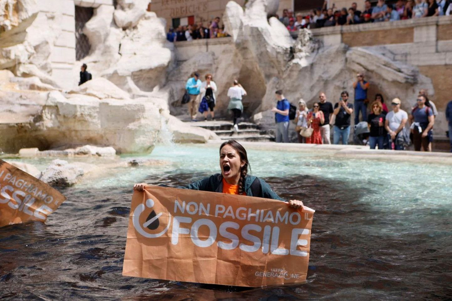 Kliimaaktivist hoidmas plakatit Trevi purskkaevus Roomas
