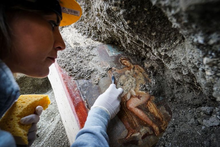 Arheoloog puhastamas 2018 Pompeis asuva kaupmehemaja seina, millel on Leda ja luigega fresko.