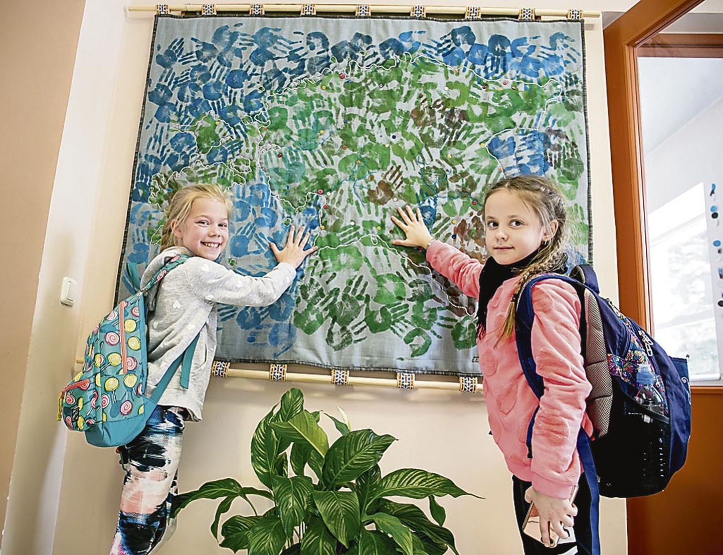 Uulu põhikooli fuajees näitavad teise klassi õpilased Saara ja Debby, kus on nende käejälg koduriigi sünnipäeva vaibal.