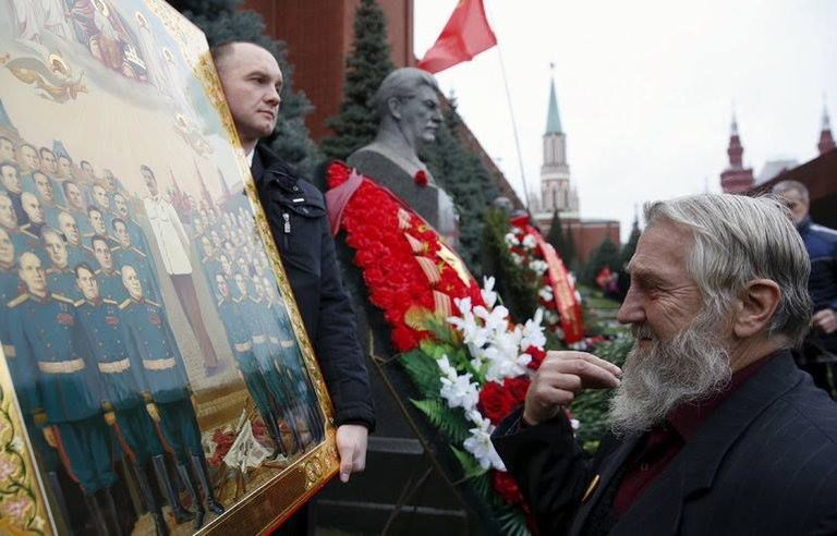 Vene mees löömas risti ette Stalini «ikooni» ees. / Scanpix
