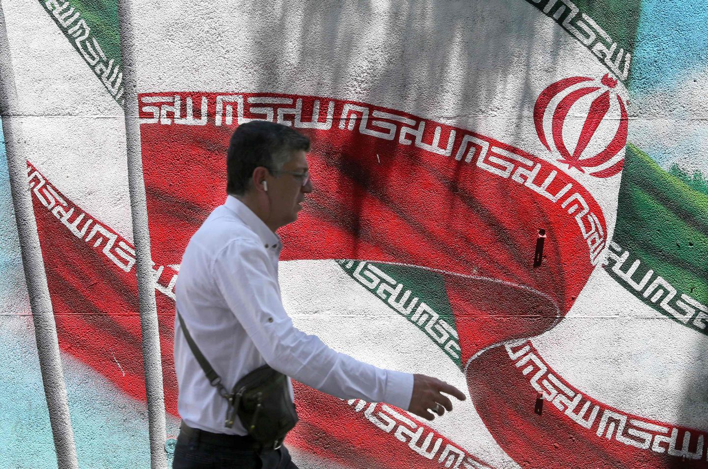 Mees Teherani tänaval Iraani lipu taustal.