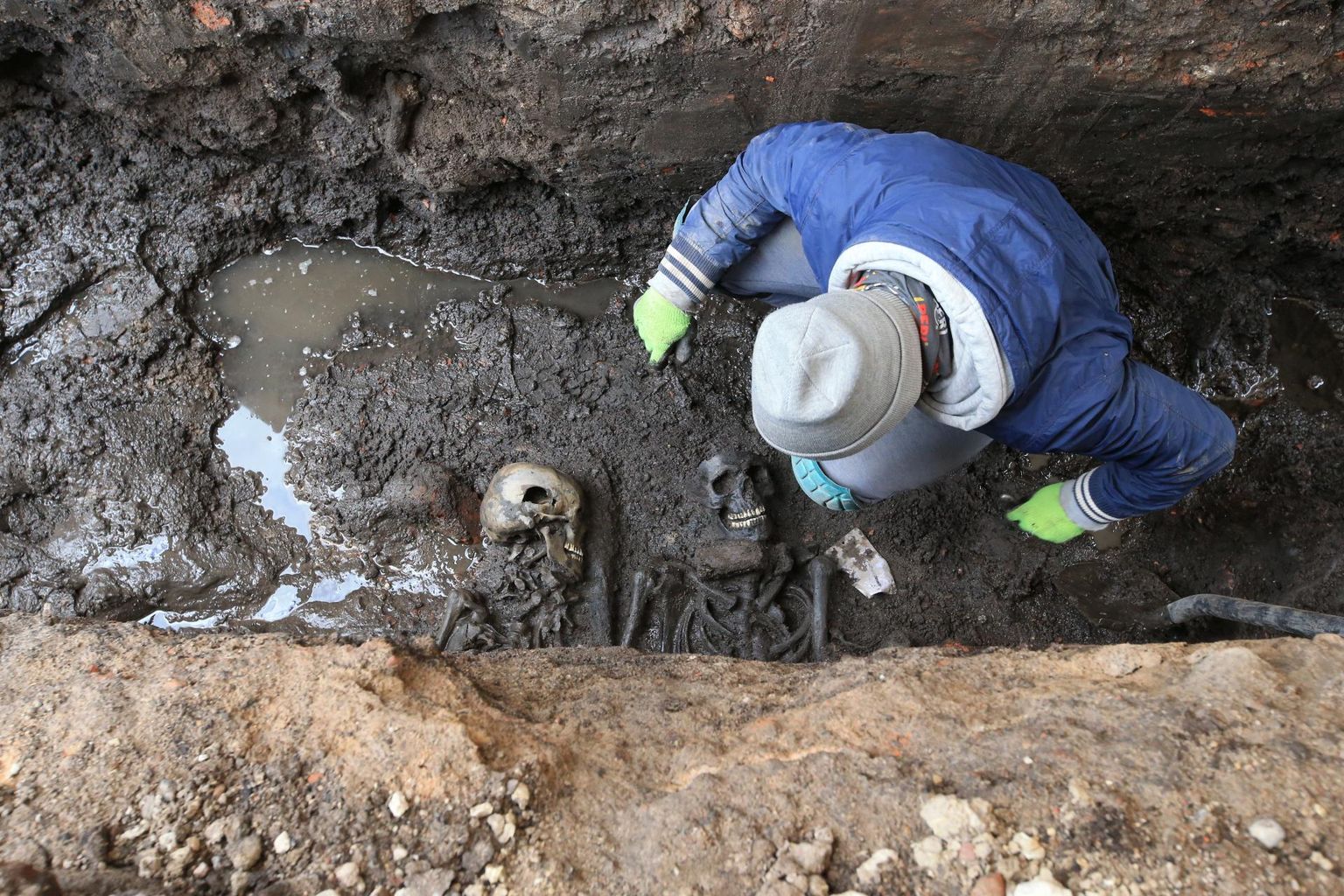Kaks noort meest Oa tänava all hauas, juba 300 aastat. Kõrval 21. sajandi arheoloogiatudeng Sander Nuut oma töövahenditega toimetamas.
