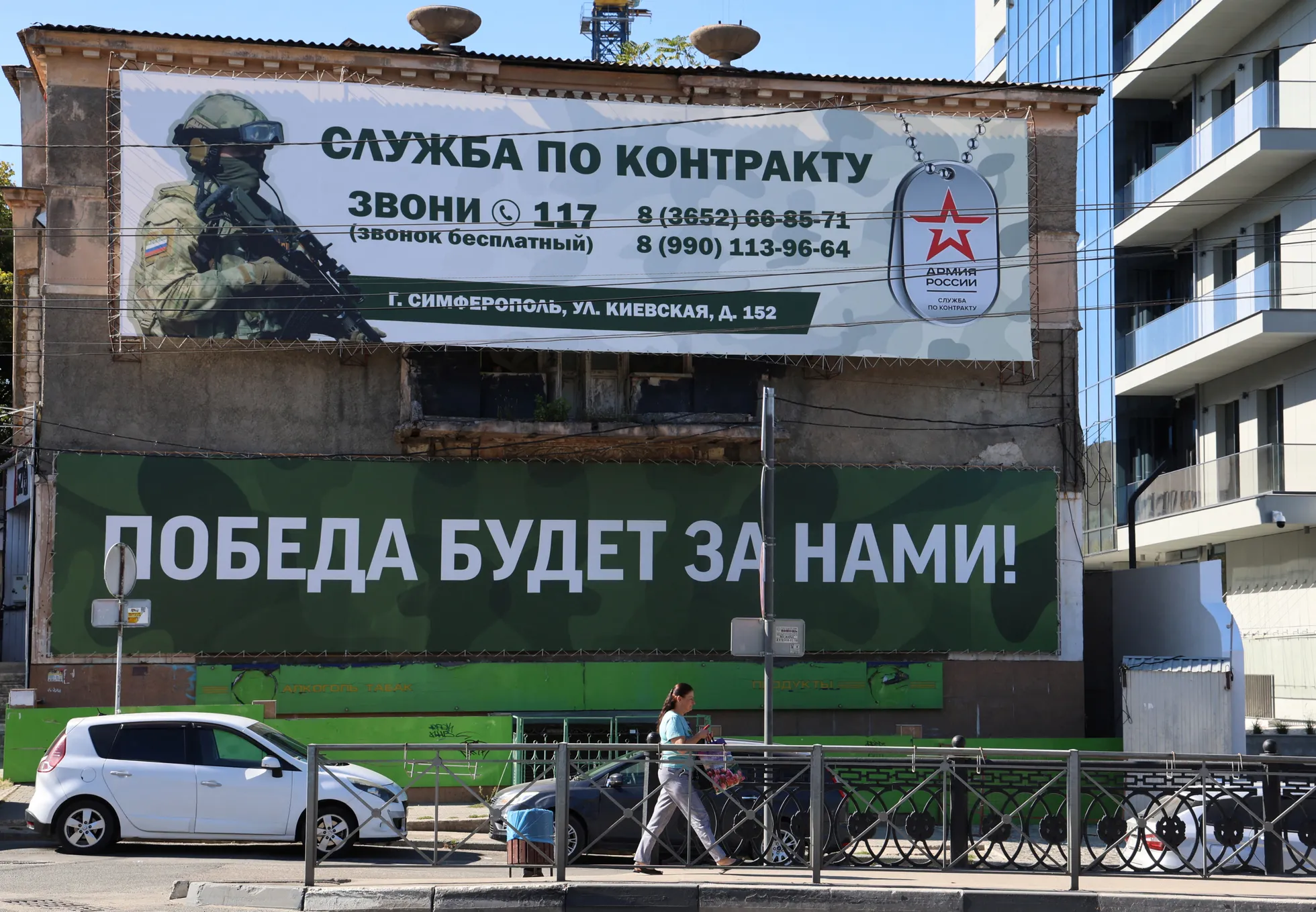 Женщина проходит мимо баннера с надписью «Победа будет за нами!», пропагандирующего военную службу по контракту в Вооруженных силах России, в Симферополе, Крым, сентябрь, 2024. REUTERS/Alexey Pavlishak