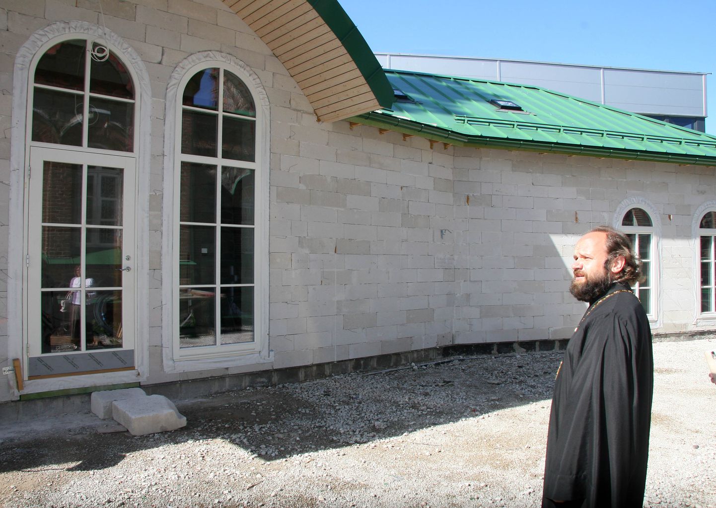 Ülempreester Andrei Suslov näitab, et tulevase pühapäevakooli seinad ja katus on valmis. Hoone vooderdamiseks punaste tellistega ja sisetöödeks kulub veel vähemalt 200 000 eurot, millest 75 000 tuleb järgmisel aastal riigikogu katuserahast.
