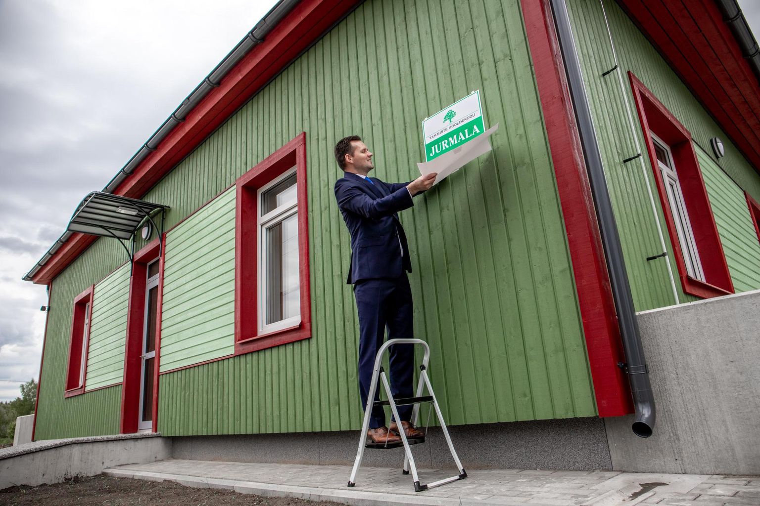 Tammiste hooldekodu kahe uue maja valmimine  -  hooldekodu juhataja Riido Villup tõmbas katte Jurmala nime kandva maja nimesildilt.