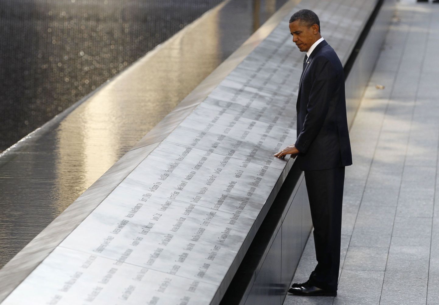 Барак Обама прикасается к табличке с именами жертв терактов, произошедших 11 сентября 2001 года.