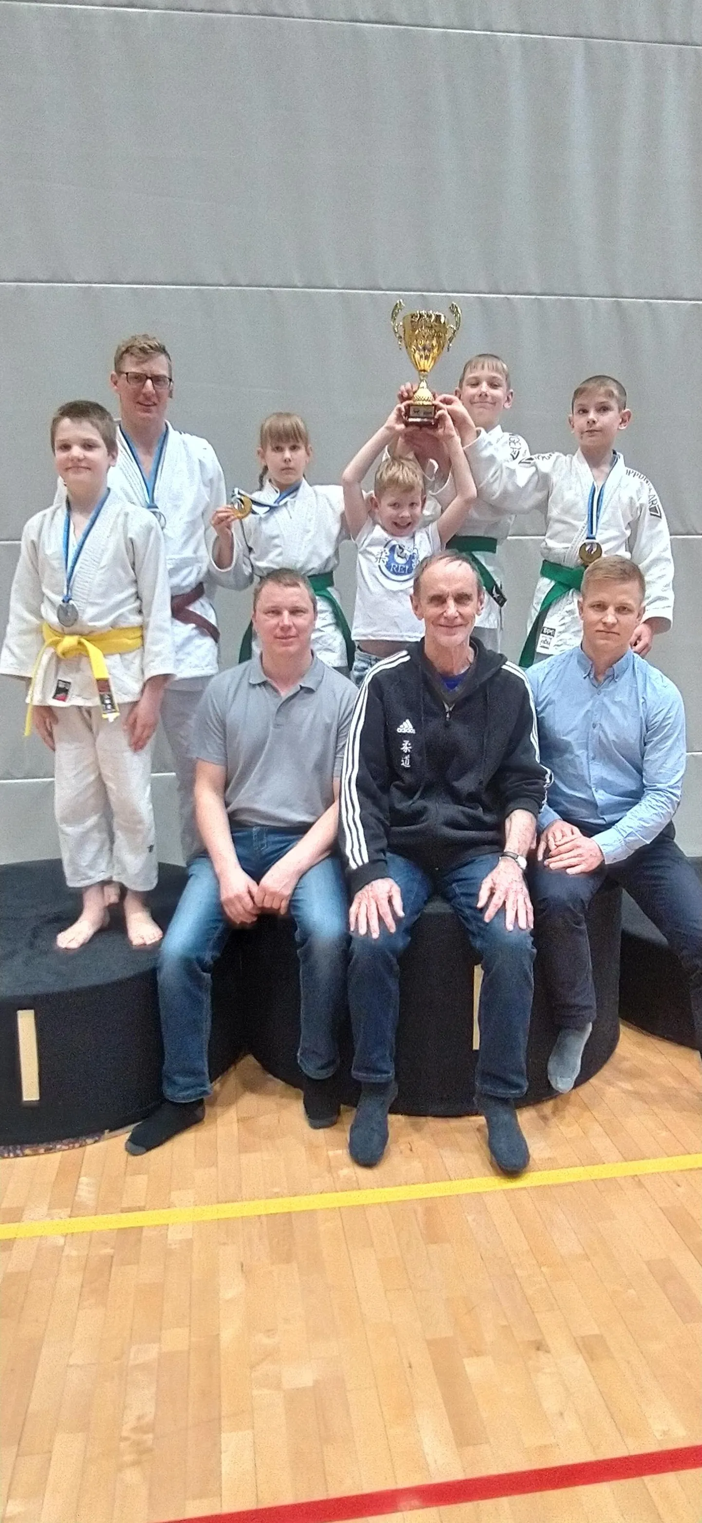 Võru judoklubi Rei medalivõitjad. Poodiumil Aho Kuks (vasakult), Janar Säkk, Saara Oja, Artur ja Oskar Trumm. Istuvad treenerid Ivar Rosenberg (vasakult), Enno Raag ja Ants-Hindrek Tiido.