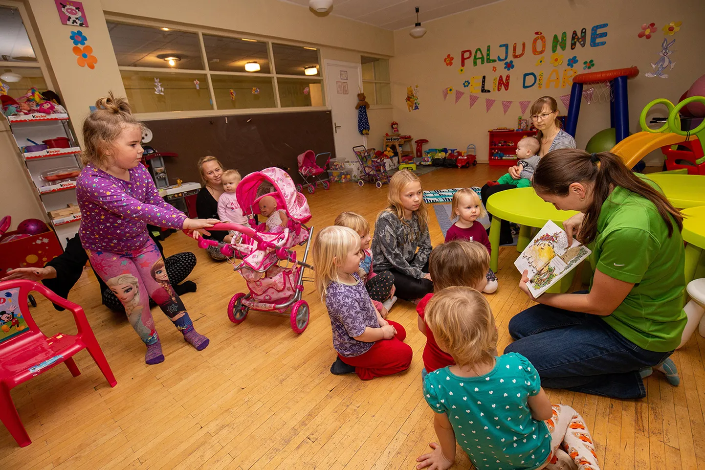 Lapsed kuulavad põnevusega, mida Kristina Kiisk neile raamatust näitab ja mis sõnu ta inglise keeles piltide kohta ütleb.