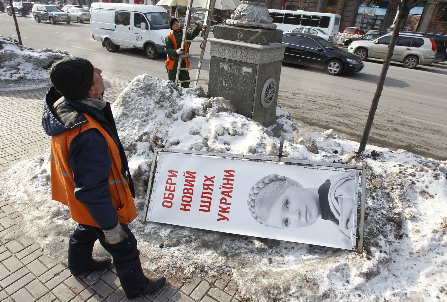 Kiievi töölised paigutavad posti otsa presidendiks kandideeriva Julia Tõmošenko näopildiga plakatit.