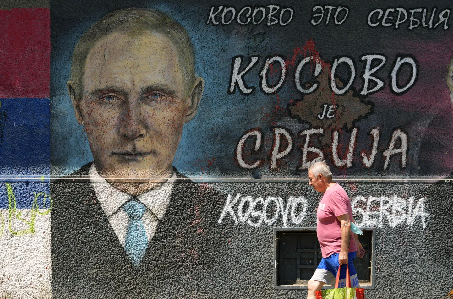 Мужчина проходит мимо граффити с изображением президента России Владимира Путина в Белграде, Сербия.