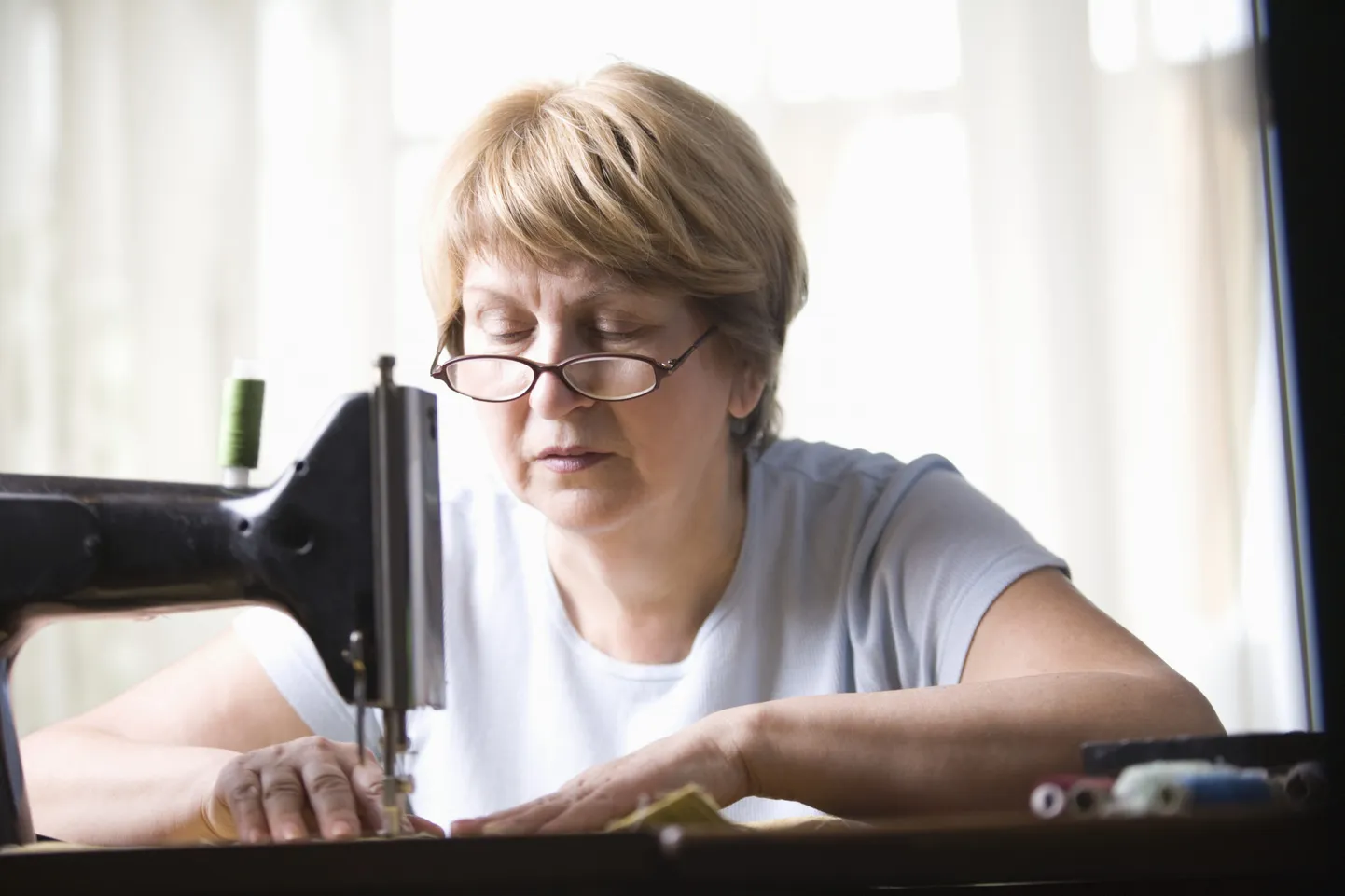 Mature woman works at sewing machine Royalty free: For comercial usage price on demand