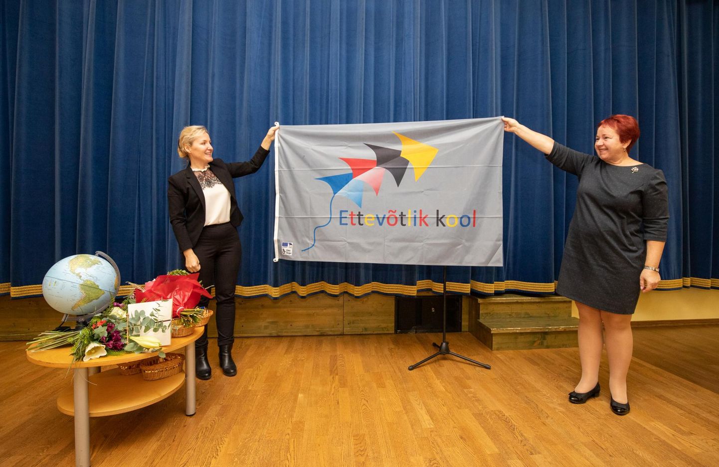 Lääne-Viru arenduskeskuse noorte ettevõtlikkuse programmi juht Anu Oja (vasakul) andis Sõmeru koolijuhile hõbetasemele jõudmise puhul üle hõbedase lipu.