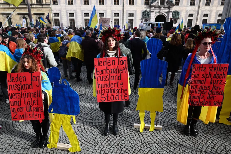 Люди с плакатами и украинскими флагами.