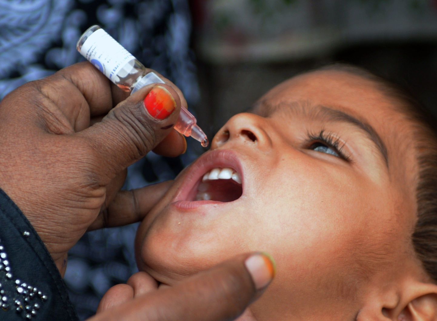 Afganistani tervisetöötaja vaktsineerib kohalikku last lastehalvatuse vastu.